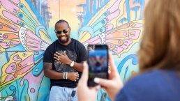 student in front of a painted mural